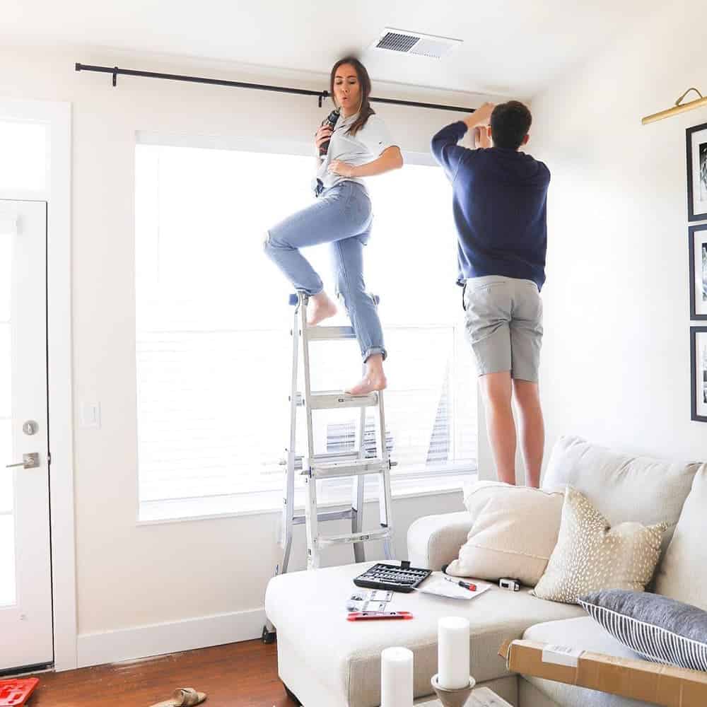 Sophia and boyfriend hanging curtains in apartment in 2020.