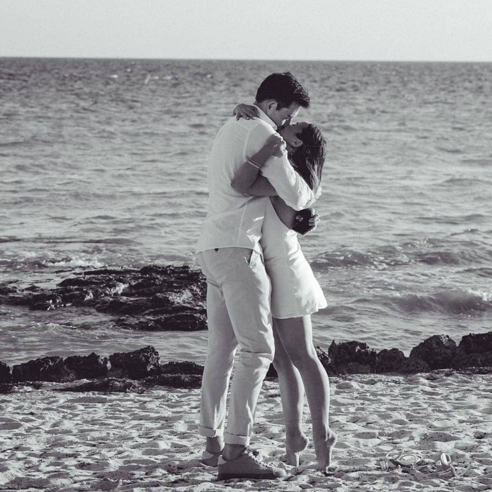 Engagement of Sophia and Ben in 2022, standing on beach kissing.
