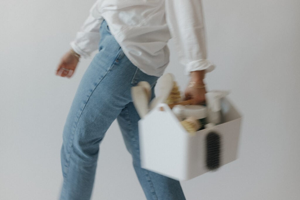 Woman walking holding cleaning caddy.